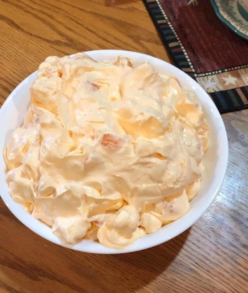 A creamy bowl of orange dreamsicle salad with Cool Whip, mandarin oranges, and marshmallows.